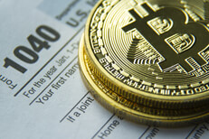 Bitcoins stacked on an IRS 1040 tax form concept image for cryptocurrency tax issues