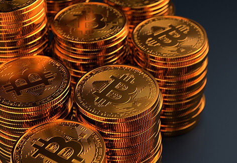 Multiple stacks of Bitcoins on dark background with stacks exiting left side of frame