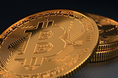 Close-up photo of Bitcoin leaning against small stack of Bitcoins