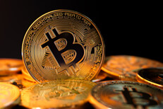Bitcoin standing on edge in pile of bitcoins with black background