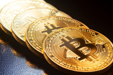 Bitcoins in a row on reflective black textured surface