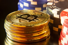 Bitcoins stacked in front of stacks of poker chips with reflection gambling concept