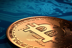 Single Bitcoin with hard spot light laying on blue circuit board