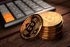 Bitcoins in front of calculator Stack of Bitcoins with one leaning in front of digital calculator