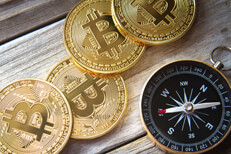 Four Bitcoins in row with compass Four Bitcoins next to navigational compass on wood planks