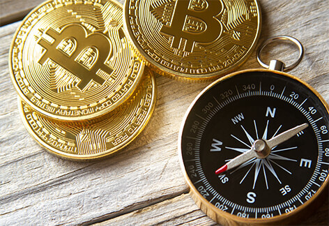 Three bitcoins with compass Three bitcoins arranged with navigational compass on weathered wood plank