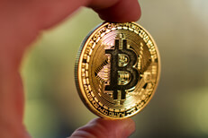 Two fingers holding Bitcoin Photo of two fingers holding a Bitcoin with short depth-of-field and background bokeh blur