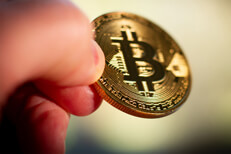 Two fingers pinching Bitcoin Photo of two fingers pinching a Bitcoin with short depth-of-field and background bokeh blur