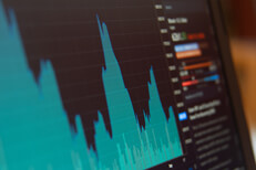 Laptop screen showing BTC stock price area chart and trading info