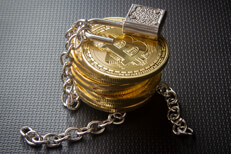 Stack of Bitcoins with unlocked padlock and loose chains on dark carbon fiber background