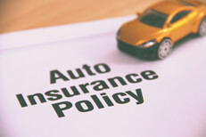 Toy car on auto insurance policy Small yellow car placed on top of an auto insurance policy on a desk