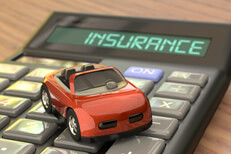 Insurance calculator with toy car Wood table with calculator with LCD reading Insurance with red toy car on top