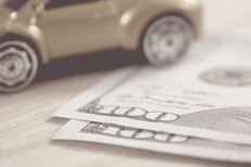 Greyscale version of toy car on wood desk with two one hundred dollar bills