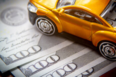 Toy car on 100 dollar bills Toy car on top of fanned 100 dollar bills car insurance cost concept photo