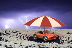 Toy car under umbrella surrounded by hail stones with lightning in sky after a hail storm