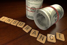 Cost of car insurance Wooden letters spell insurance with two rolls of 100 dollar bills