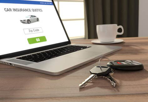 Laptop showing car insurance quotes website with coffee and keys on desk