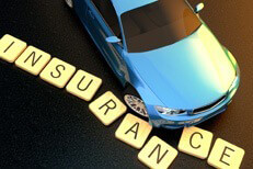 Car accident insurance concept Concept image of blue car at sunset skidding through insurance letters on asphalt