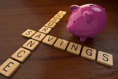 Insurance savings concept Insurance savings spelled out in wooden letters next to pink piggy bank on desk