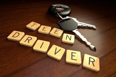 Teenage driver car insurance concept Teen driver in wooden letters with car keys on wooden desk