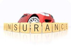 Insurance letters concept Low fish eye viewpoint of wooden insurance letters wrapped around red sports car