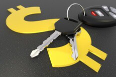 Car keys and key fob on top of shiny gold dollar sign