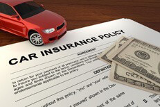 Car insurance policy on desk with red car and one hundred dollar bills