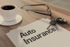 Auto insurance papers on desk Auto insurance policy concept with glasses, car keys, and coffee on desk