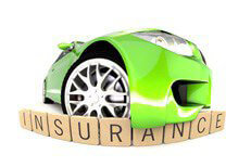 Green sports car with bumper hanging over wood insurance letters fish eye view