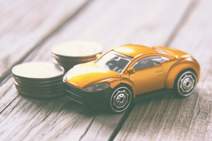 Small toy car on wood planks with stacks of coins