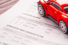 Car insurance policy showing driver information Auto insurance policy showing coverages and driver information with red toy car