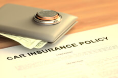 Wallet on car insurance policy Wallet with cash and stack of coins on table with car insurance policy