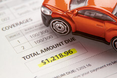 Car insurance bill showing premium due Toy car sitting on car insurance bill with payment due highlighted in yellow