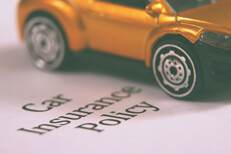 Close up of car with car insurance policy Close up view of small car on top of car insurance policy
