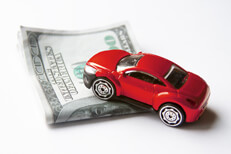 Car climbing money Toy car climbing stack of folded money automotive cost or cost of insurance concept