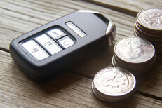 Keyless entry remote with coin stacks Car insurance cost concept photo of remote entry and stacks of coins