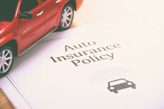 Auto insurance policy with red SUV sitting on it