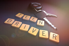 Teen driver letter with keys and flare Concept for teen drivers and car insurance with wood letters, car keys, and overlay with lens flare