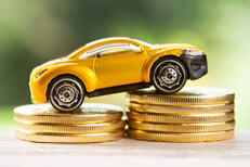 Yellow toy car on coin stacks Yellow toy car climbing two stacks of gold coins