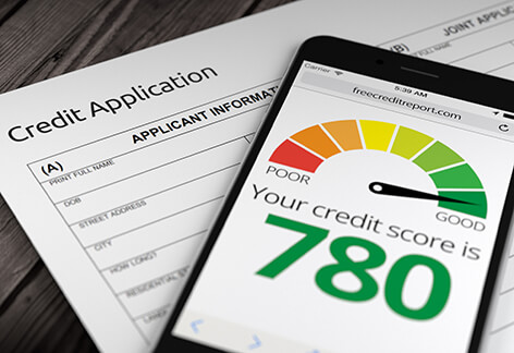 Paper credit application on desk with mobile phone showing good credit score of 780