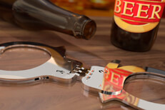 Beer bottles on bar with hand cuffs concept for DUI or drunk driving arrest