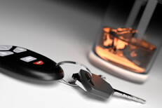 Drunk driving concept showing whiskey glass and car keys on white studio background