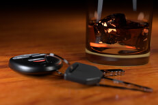 Drunk driving concept showing whiskey glass and car keys on bar top