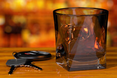 Whiskey glass and keys at bar Whiskey glass and car keys on bar with liquor bottle background DUI concept