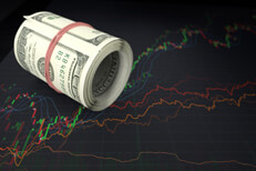 Large roll of U.S. bills laying on top of line charts showing massive stock price fluctuation