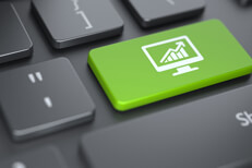 Monitor investments key Dark computer keyboard with bright green key showing a monitor with increasing column chart