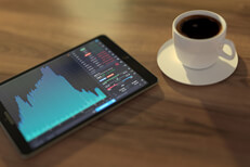iPad stock price with coffee Table with iPad showing stock price information, investment portfolio, and cup of coffee