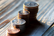 Increasing stacks of coins hard light Increasing stacks of pennies, nickels, dimes, and quarters like chart in morning light