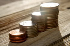 Increasing stacks of coins sun flare Increasing stacks of pennies, nickels, dimes, and quarters like chart with sun flare