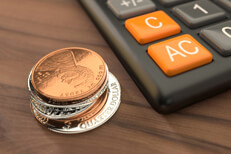 Coins next to calculator Stack of coins next to calculator on wood table top